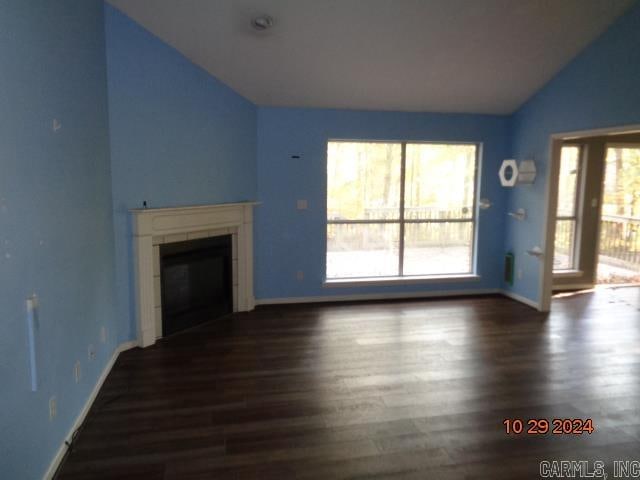 unfurnished living room featuring a tile fireplace, dark hardwood / wood-style flooring, and vaulted ceiling