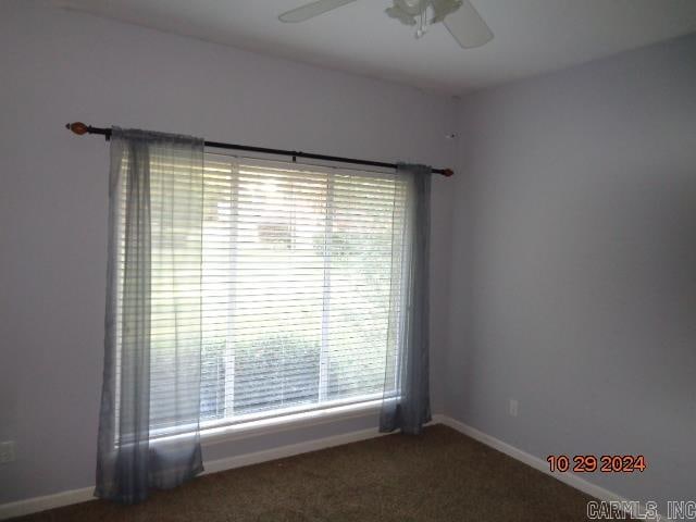 carpeted spare room featuring ceiling fan and plenty of natural light