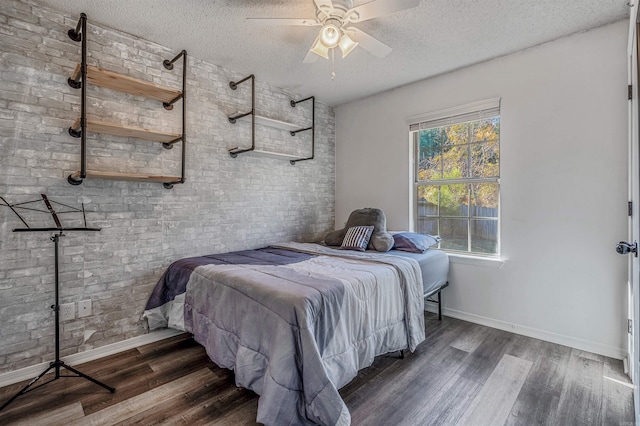 bedroom with a textured ceiling, dark hardwood / wood-style floors, ceiling fan, and brick wall