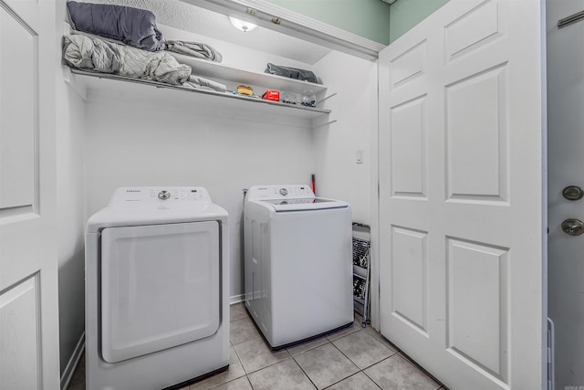 clothes washing area featuring washer and clothes dryer, light tile patterned flooring, and a textured ceiling