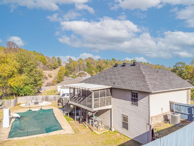 back of house featuring a sunroom, central AC unit, a patio area, and a covered pool