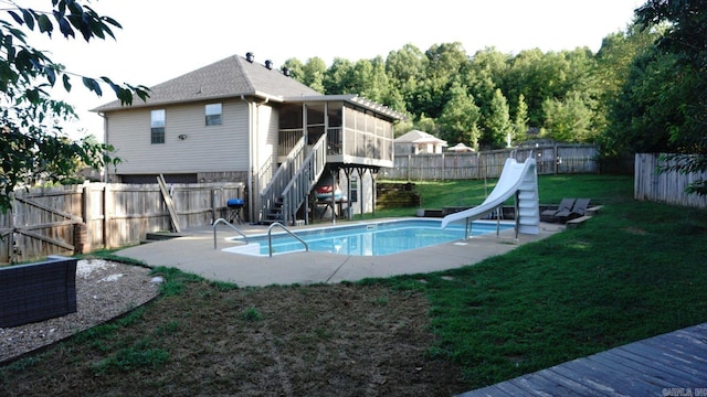 view of swimming pool featuring a sunroom, a lawn, and a water slide