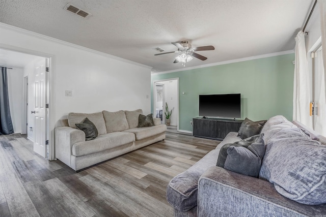 living room with hardwood / wood-style flooring, crown molding, and a textured ceiling