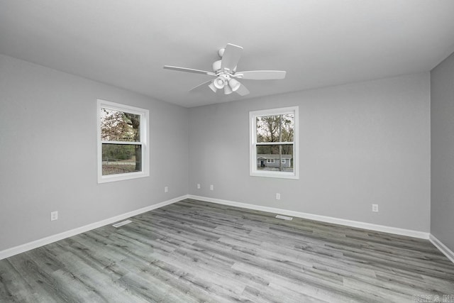 empty room featuring plenty of natural light, light hardwood / wood-style floors, and ceiling fan