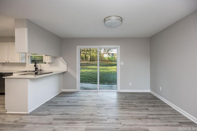 kitchen with backsplash, kitchen peninsula, white cabinets, and light hardwood / wood-style floors