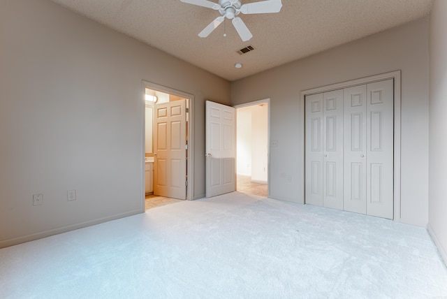 unfurnished bedroom featuring a textured ceiling, a closet, ceiling fan, and light colored carpet