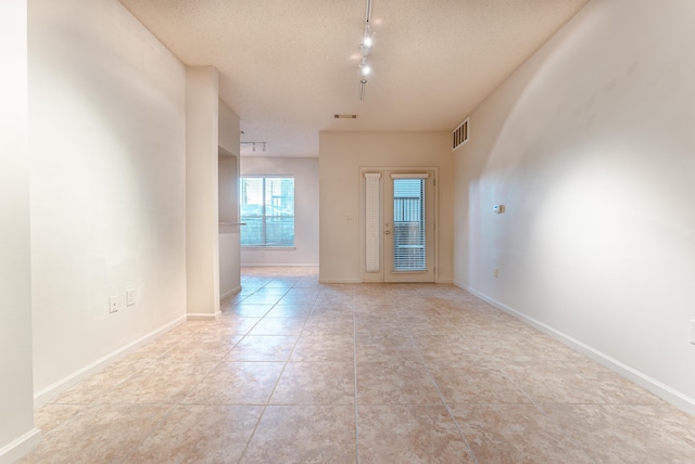 tiled spare room featuring a textured ceiling