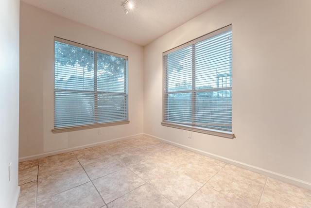 spare room with light tile patterned floors and a textured ceiling