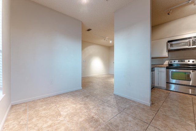 kitchen with light tile patterned floors, rail lighting, a textured ceiling, and appliances with stainless steel finishes