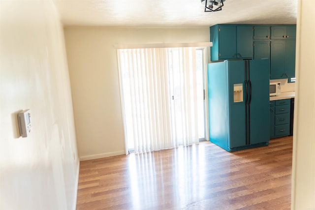 kitchen featuring a textured ceiling, light wood-type flooring, black refrigerator with ice dispenser, and a wealth of natural light