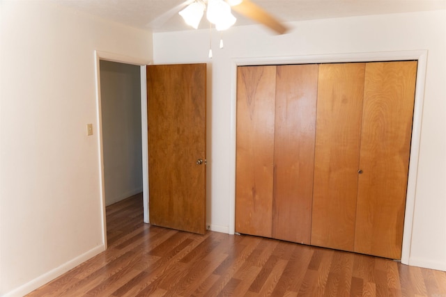 unfurnished bedroom featuring ceiling fan, a closet, and dark wood-type flooring