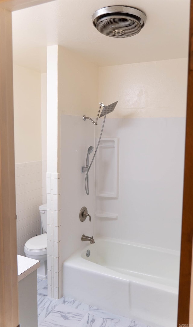 full bathroom with vanity, washtub / shower combination, tile walls, and toilet