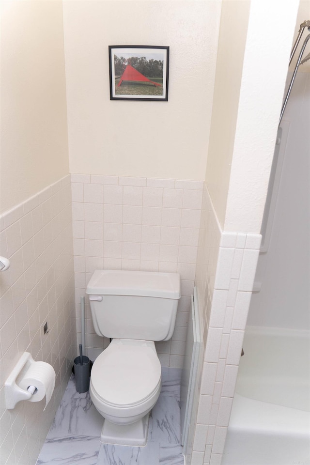 bathroom featuring toilet and tile walls