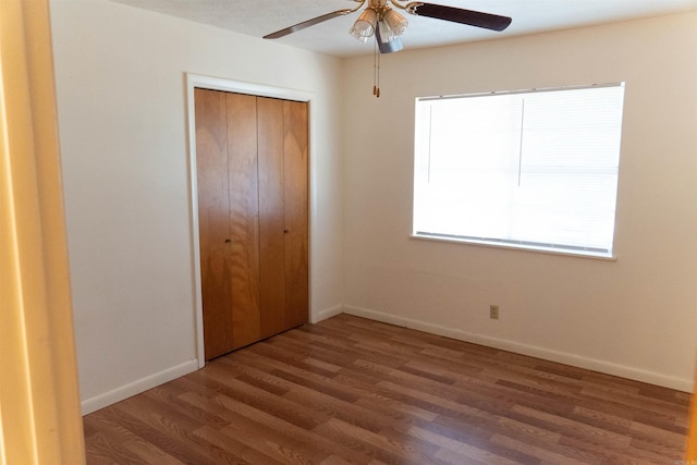 unfurnished bedroom featuring ceiling fan, dark wood-type flooring, and a closet