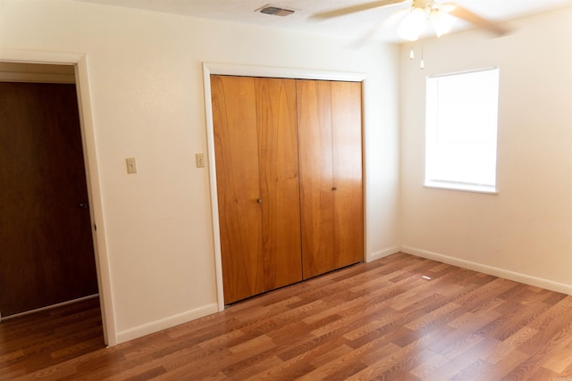 unfurnished bedroom featuring wood-type flooring, a closet, and ceiling fan