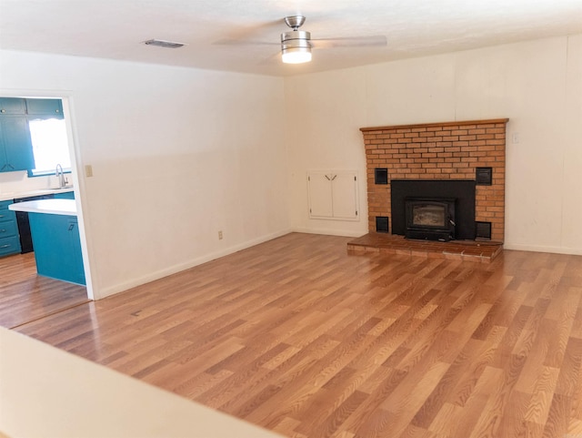 unfurnished living room featuring ceiling fan, sink, and light hardwood / wood-style floors