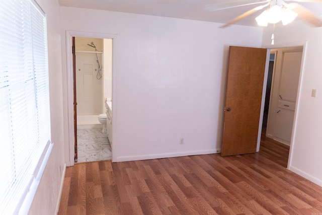 unfurnished bedroom featuring ceiling fan, a spacious closet, dark wood-type flooring, and a closet