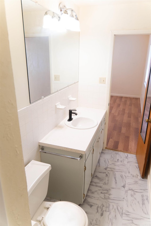 bathroom with vanity, tile walls, and toilet