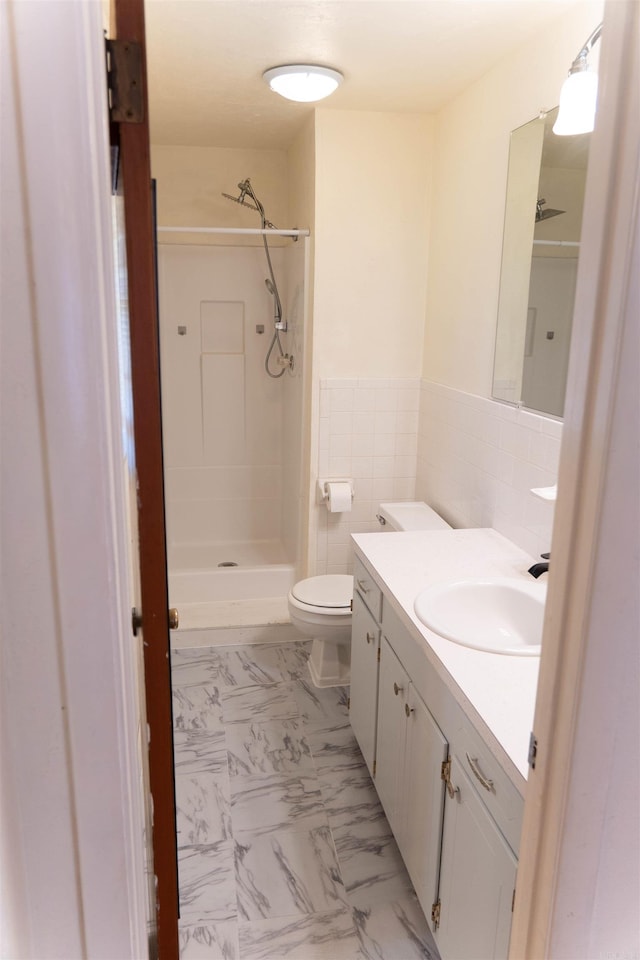 bathroom featuring vanity, toilet, walk in shower, and tile walls