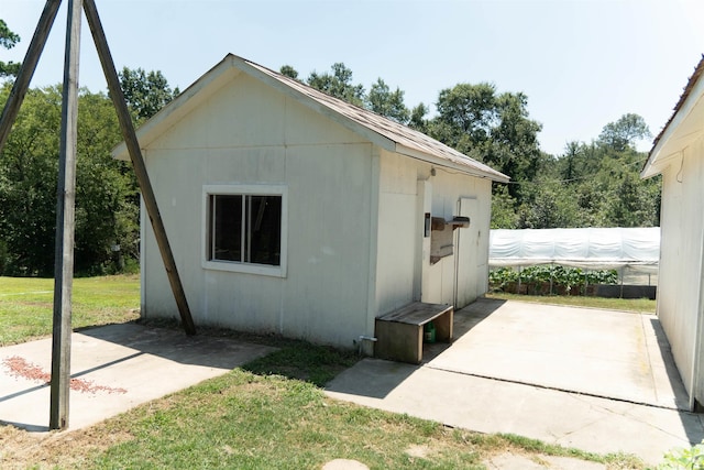 view of side of property featuring a lawn, a patio area, and an outdoor structure