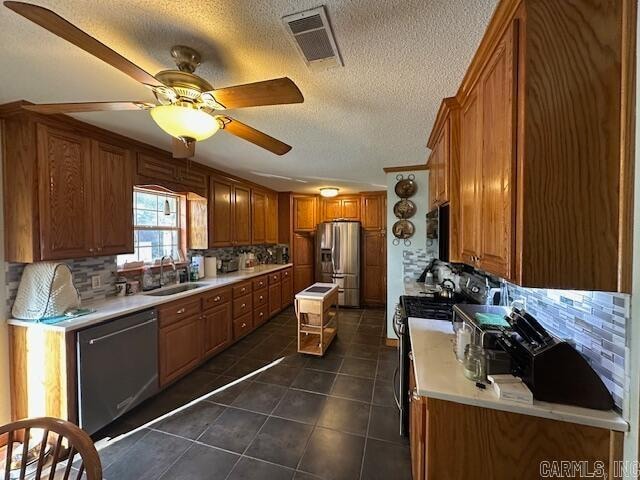 kitchen featuring tasteful backsplash, stainless steel appliances, ceiling fan, dark tile patterned floors, and sink