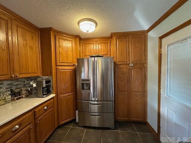 kitchen with dark tile patterned flooring, decorative backsplash, stainless steel fridge with ice dispenser, and crown molding