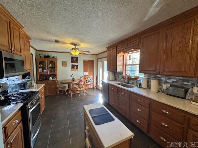 kitchen with backsplash, ceiling fan, sink, and appliances with stainless steel finishes