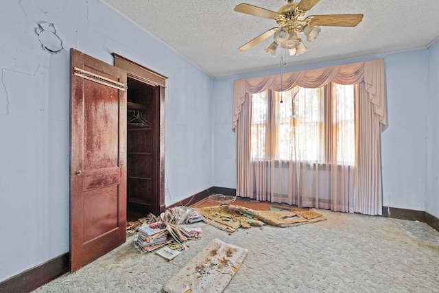 unfurnished bedroom featuring a textured ceiling, a closet, dark carpet, and ceiling fan