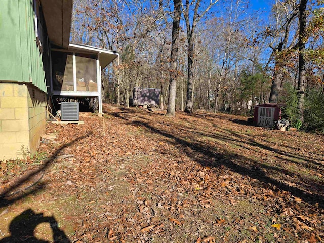 view of yard featuring a sunroom, central AC unit, and a storage unit