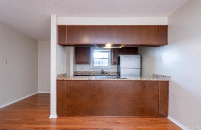 kitchen with light wood-type flooring, a textured ceiling, and white refrigerator