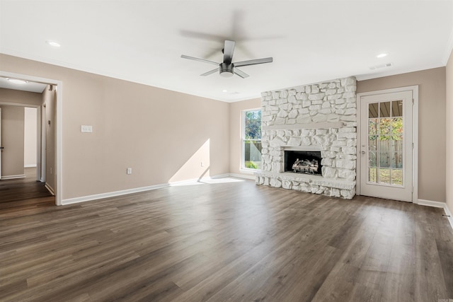 unfurnished living room with ceiling fan, a stone fireplace, dark hardwood / wood-style flooring, and ornamental molding