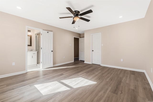 unfurnished bedroom with ensuite bath, ceiling fan, and light wood-type flooring