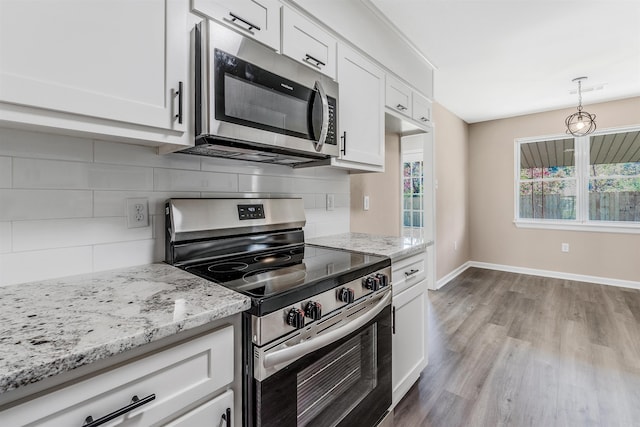 kitchen featuring decorative backsplash, stainless steel appliances, pendant lighting, light hardwood / wood-style flooring, and white cabinets