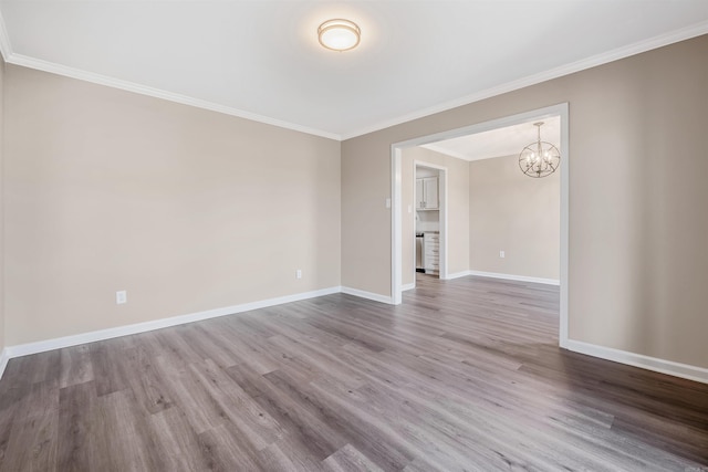 empty room with hardwood / wood-style floors, ornamental molding, and a notable chandelier