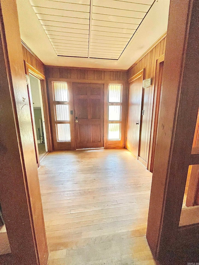 hallway featuring light wood-type flooring and wooden walls