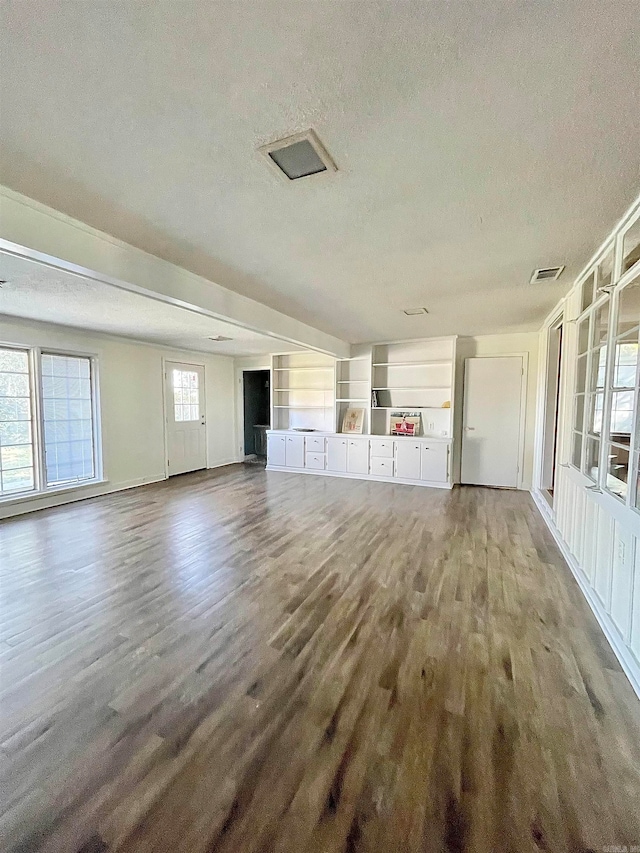 unfurnished living room with dark hardwood / wood-style flooring and a textured ceiling