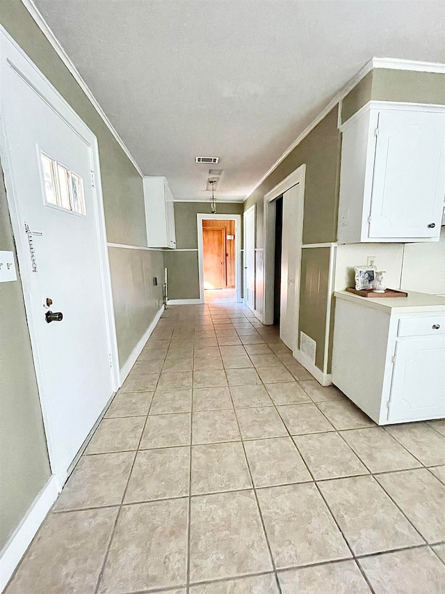 hall with crown molding, light tile patterned floors, and a textured ceiling