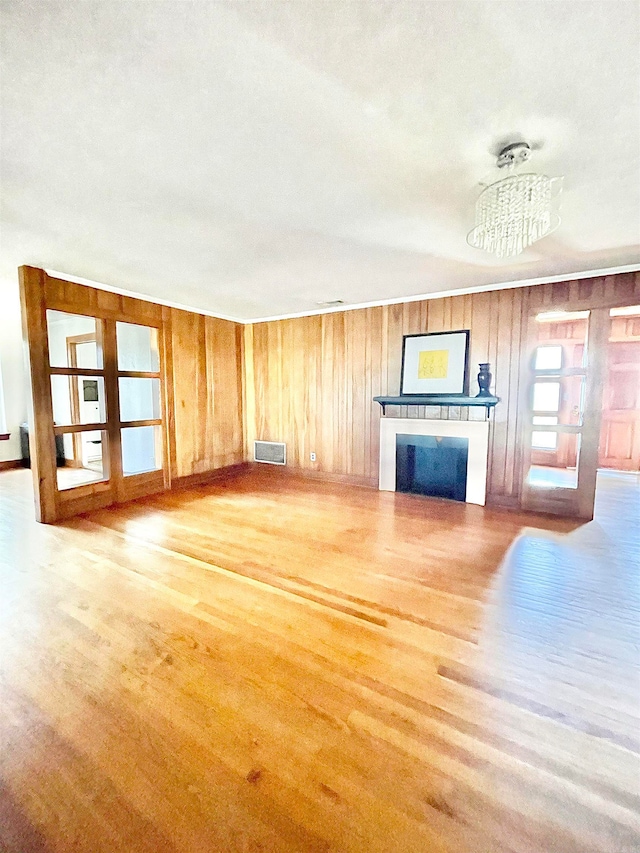 unfurnished living room featuring wood walls, a textured ceiling, and a notable chandelier