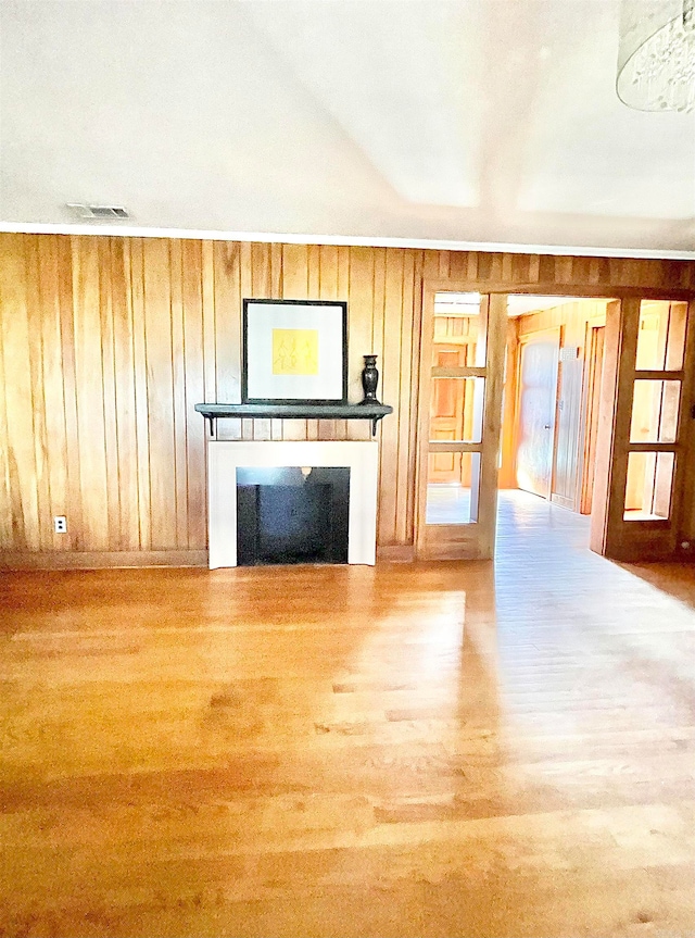 unfurnished living room with hardwood / wood-style floors and wooden walls