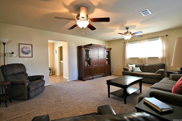 living room with ceiling fan, light colored carpet, and a textured ceiling