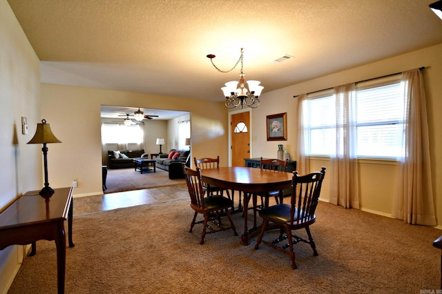 carpeted dining area featuring ceiling fan with notable chandelier and a textured ceiling