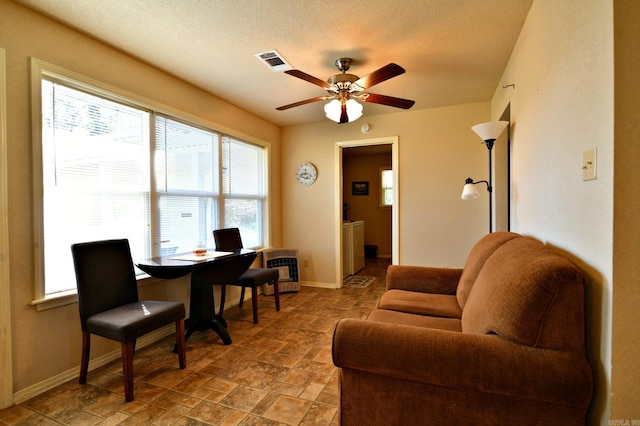 living room featuring ceiling fan, a textured ceiling, and heating unit