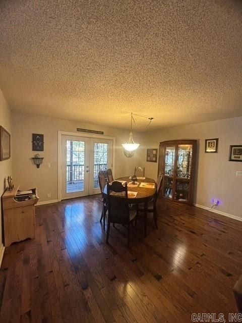 dining area with french doors, a textured ceiling, and dark wood-type flooring