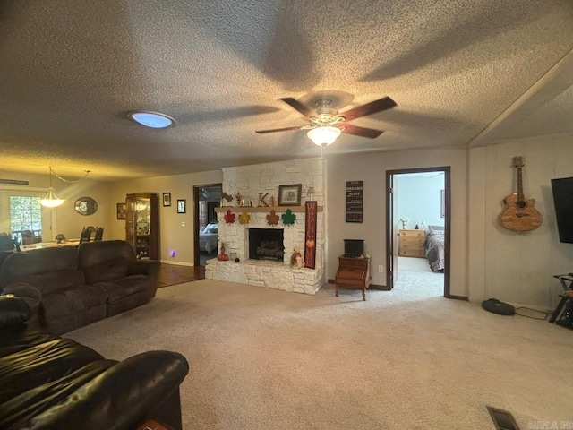 carpeted living room with a fireplace, a textured ceiling, and ceiling fan