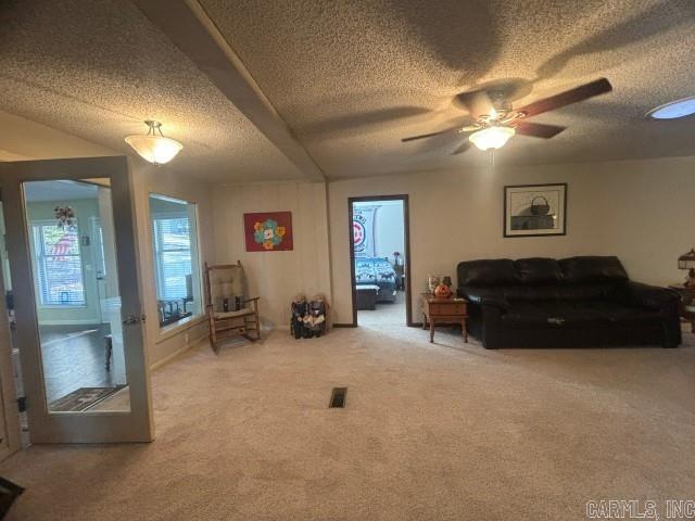 carpeted living room featuring a textured ceiling and ceiling fan