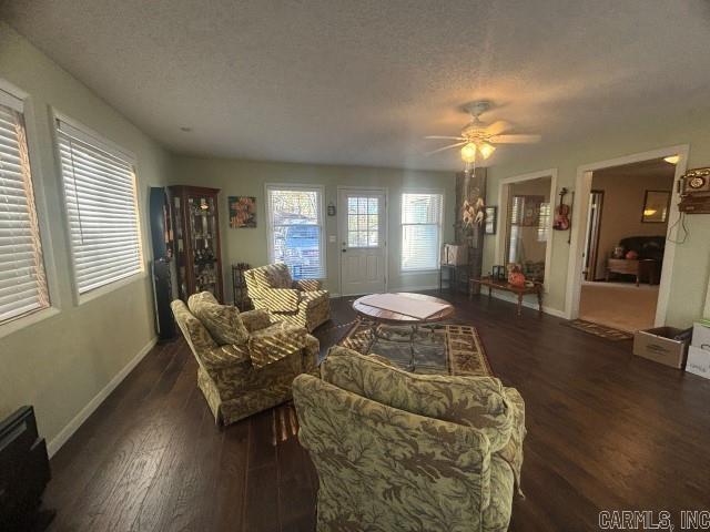 living room featuring a textured ceiling, ceiling fan, and dark wood-type flooring