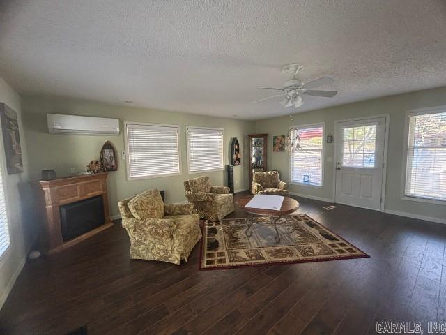 living room featuring an AC wall unit, a wealth of natural light, a textured ceiling, and dark hardwood / wood-style floors