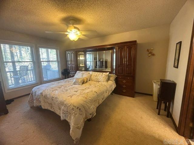 carpeted bedroom with ceiling fan and a textured ceiling