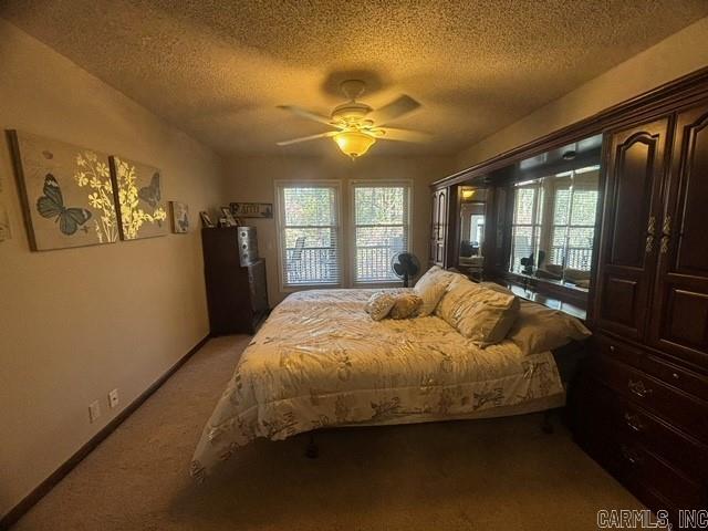 carpeted bedroom with ceiling fan, a textured ceiling, and access to outside