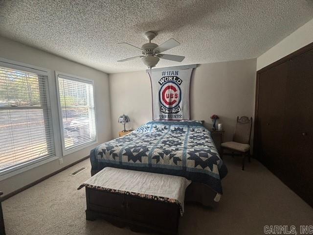 bedroom featuring carpet flooring, a textured ceiling, and ceiling fan